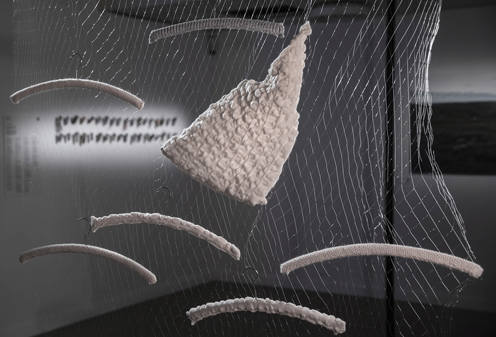 Close-up of installation showing white curved cloth hangers and netting